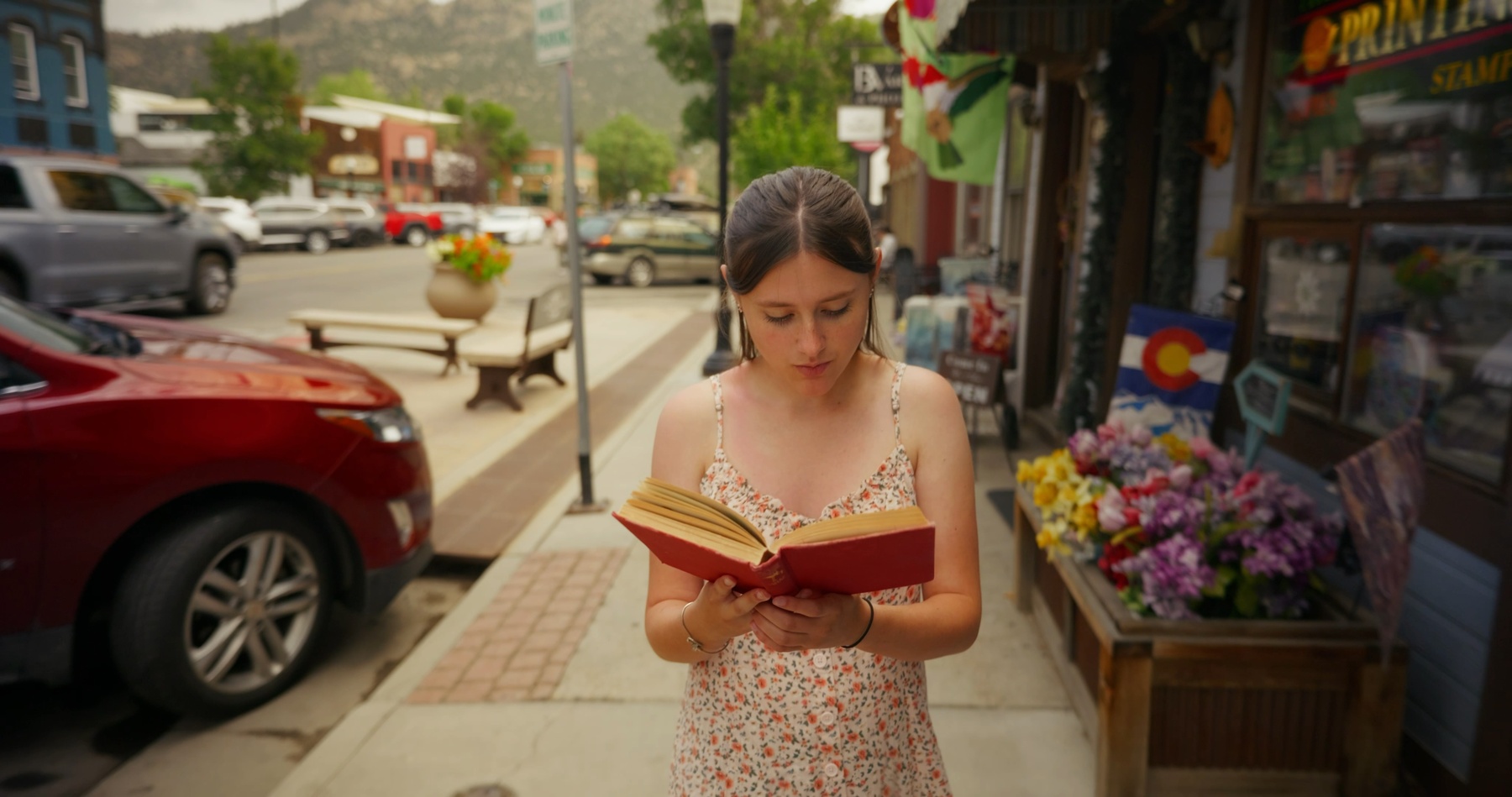Olivia holds a red novel at the counter of the Blend.