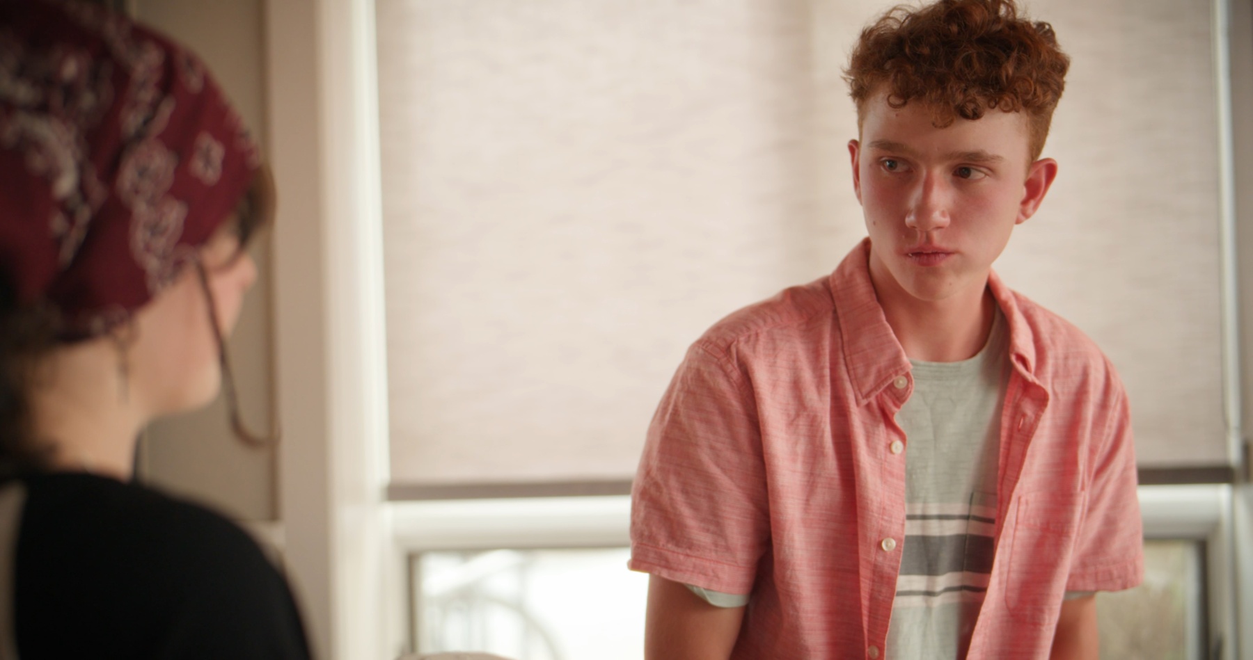 Ryan talks with Maddy near a sunlit window.
