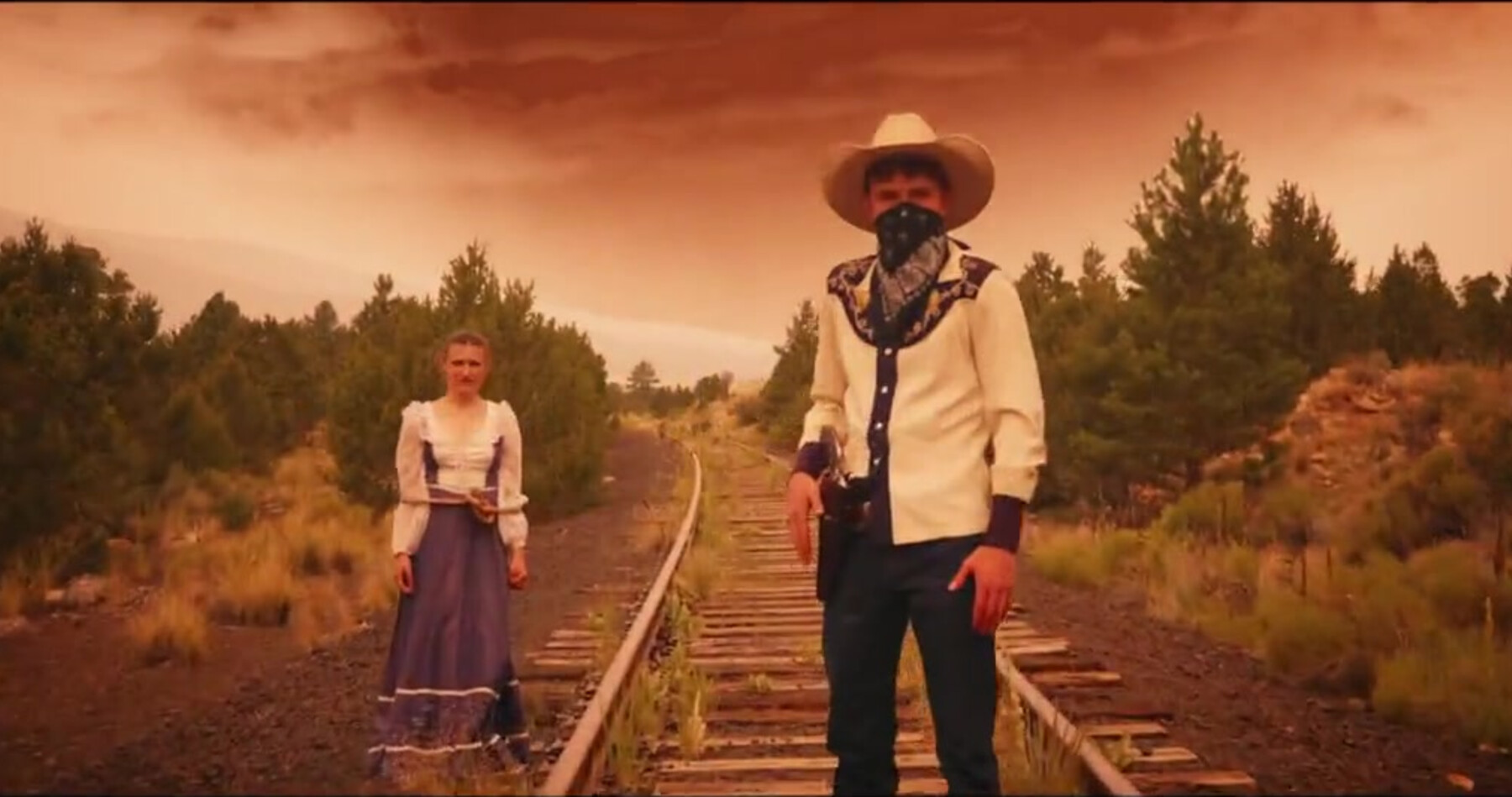 A masked figure and a woman in period dress face off on train tracks in Olivia's daydream.