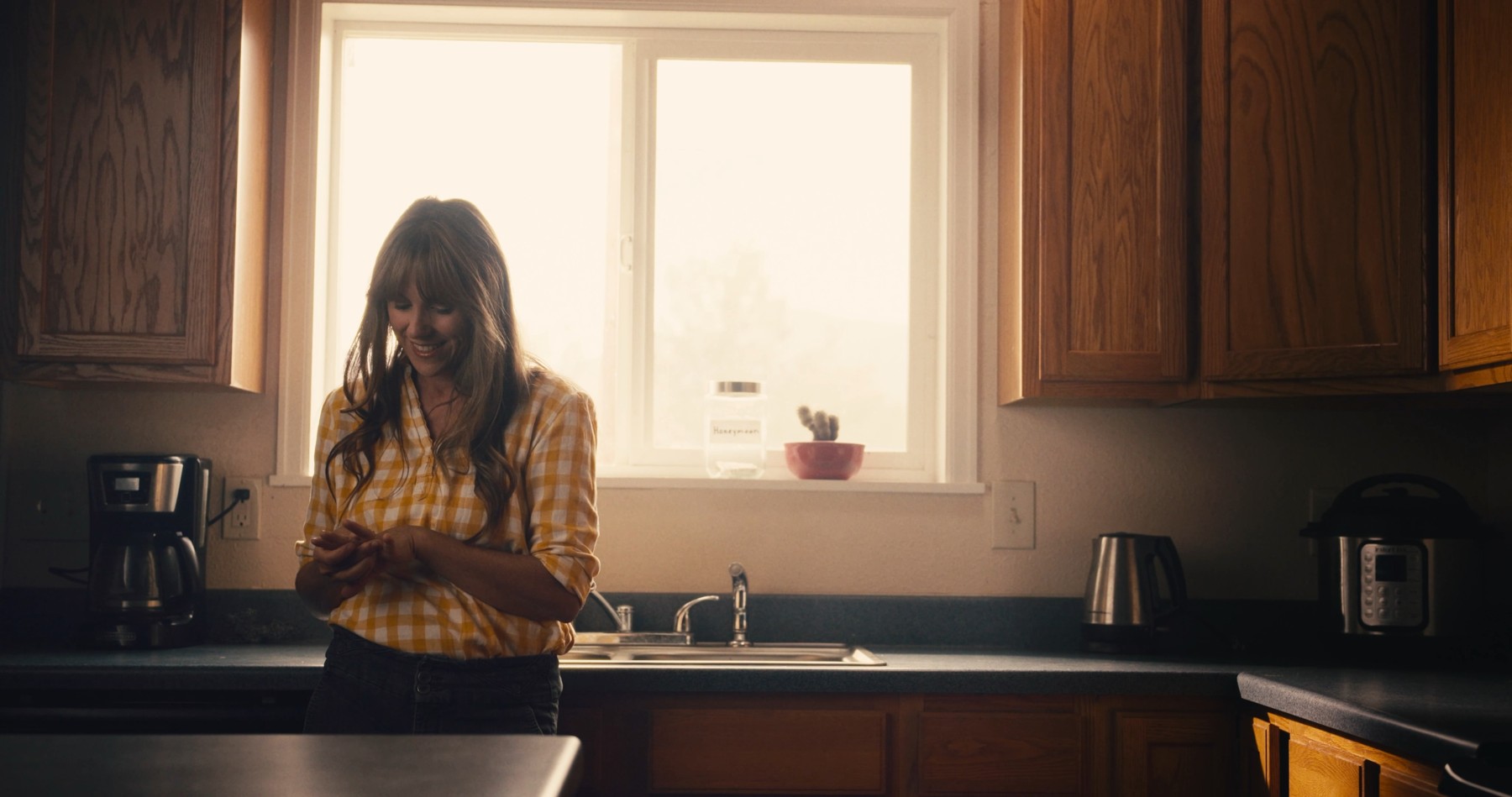 Maggie stands at a sunlit kitchen window.